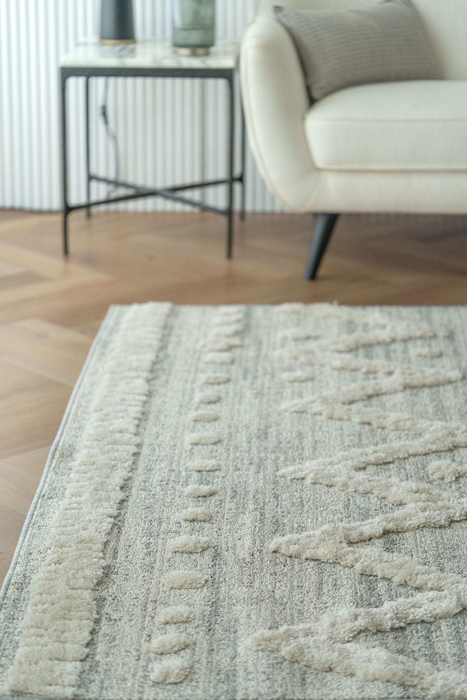 Close-up of a pale patterned carpet beside living room seating